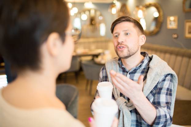 Emotional man speaking to colleague in cafe