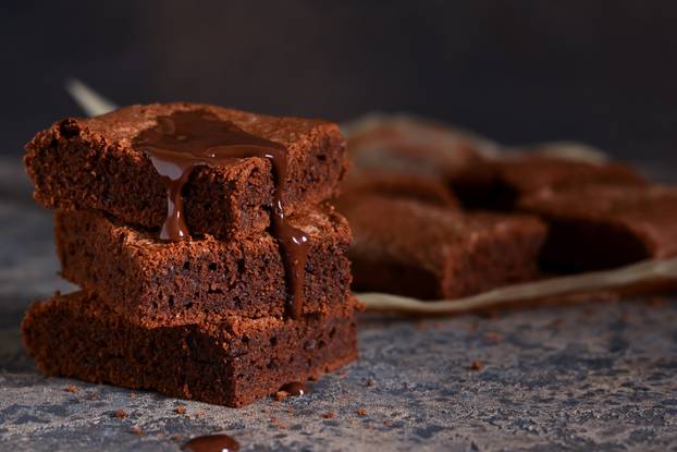 Brownie is a classic American dessert. Pie with chocolate sauce on a dark background.