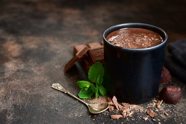 Homemade hot chocolate with mint in a black mug.