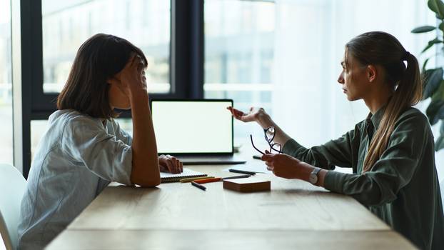 Two serious businesswomen having a meeting using laptop in office