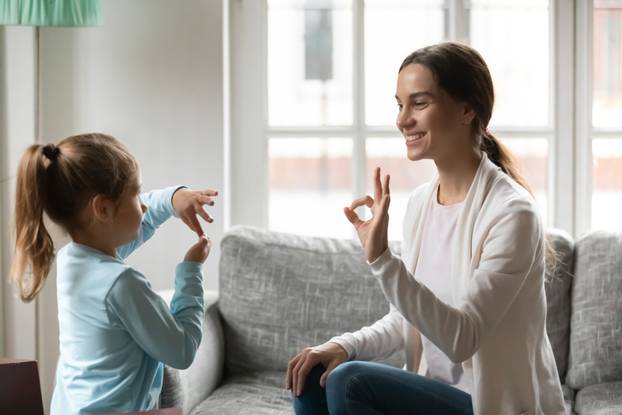 Young mom practice sign language with little daughter