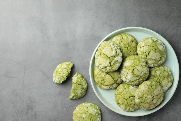 Plate with tasty matcha cookies on grey table, flat lay. Space f