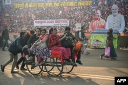 Laborers ferry Hindu pilgrims past a poster of Indian Prime Minister Narendra Modi, right, and Uttar Pradesh state Chief Minister Yogi Adityanath during the ongoing Maha Kumbh festival in Prayagraj on Feb. 1, 2025.