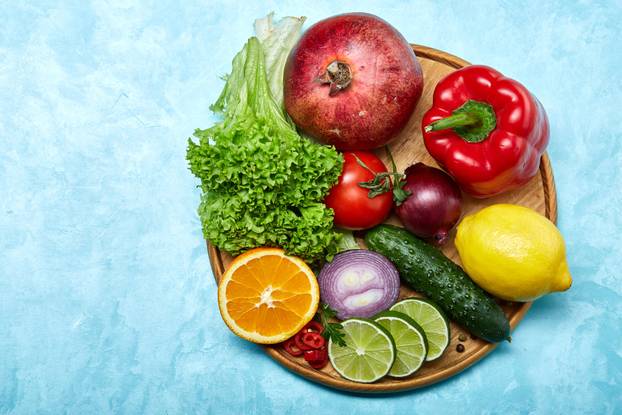 Still life of fresh organic vegetables on wooden plate over blue background, selective focus, close-up