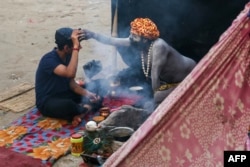 A man seeks blessings from a sadhu, or Hindu holy man, inside his tent on the banks of the Ganges River in Varanasi, India, on Feb. 20, 2025.